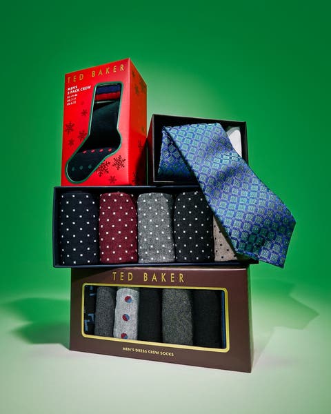 Stacked gift boxes of men's socks and a blue patterned tie on green.
