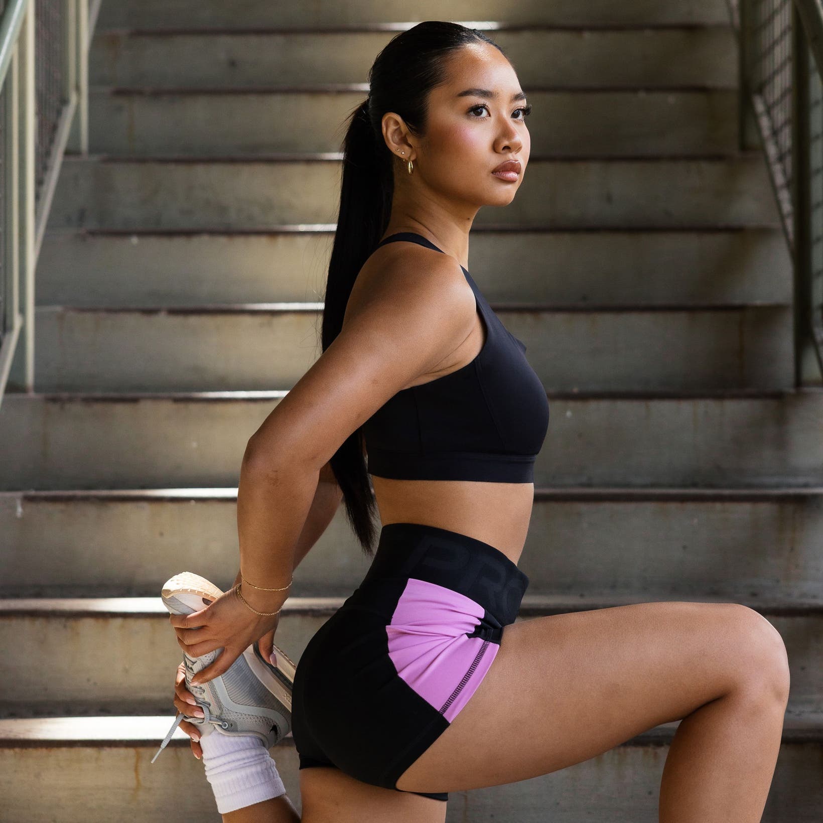 A woman stretching and wearing Nike Pegasus Premium running shoes.