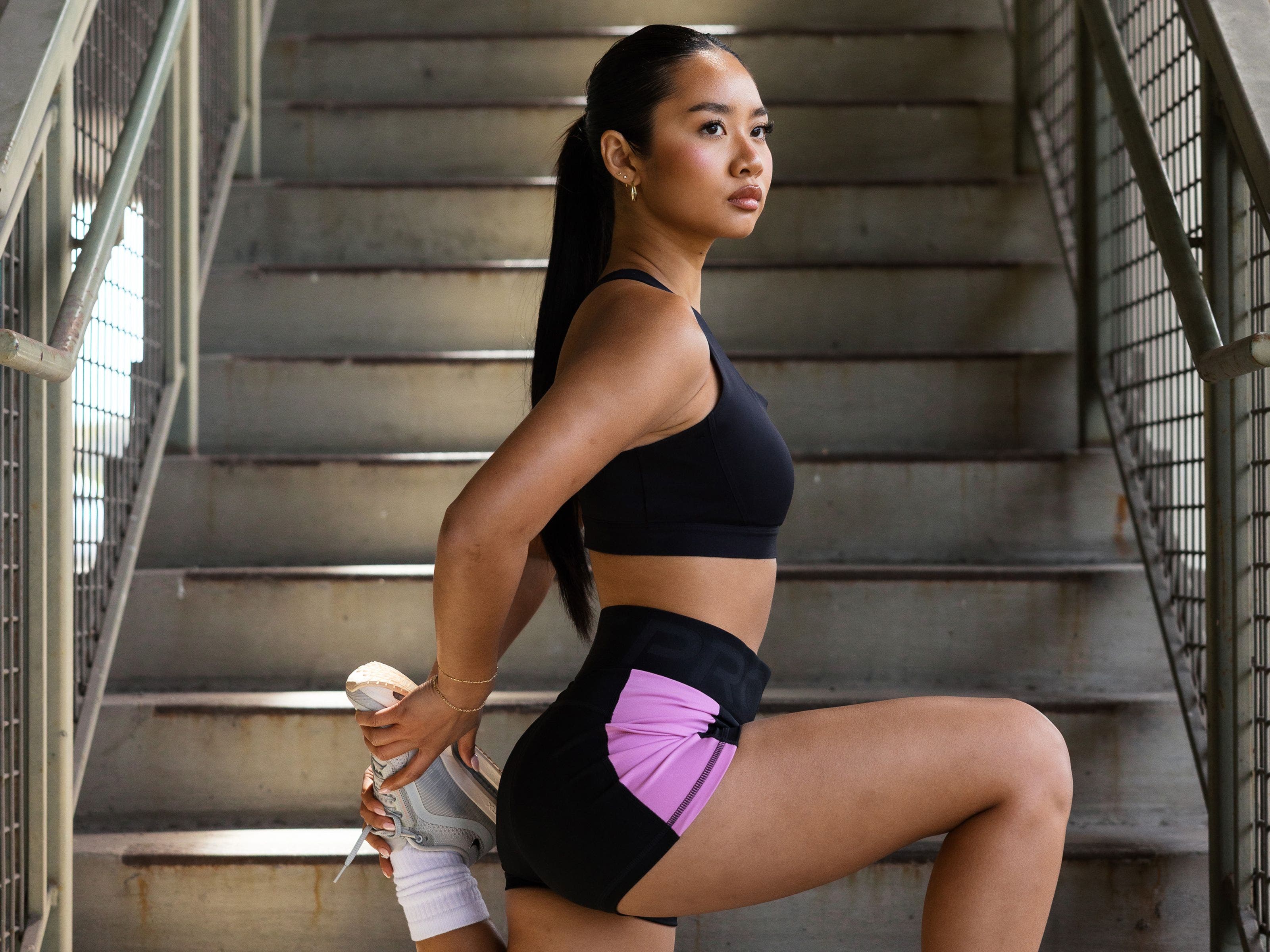 A woman stretching and wearing Nike Pegasus Premium running shoes.