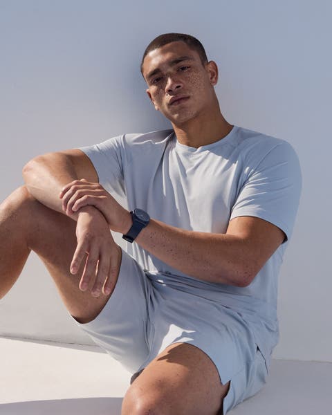 A man wearing a pale blue tee and shorts.