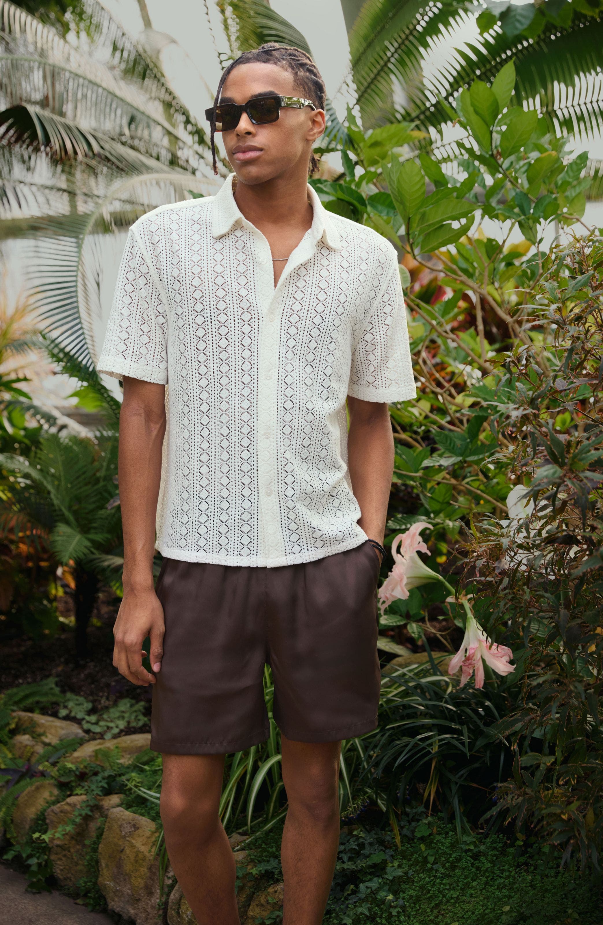 Man wearing open knit button-up and brown linen shorts.