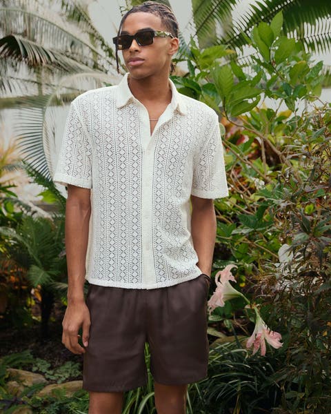 Man wearing open knit button-up and brown linen shorts.