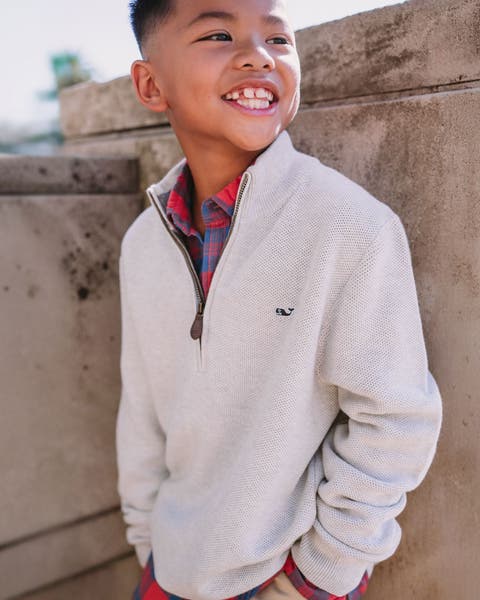 Boy wearing a half-zip sweatshirt and flannel shirt.