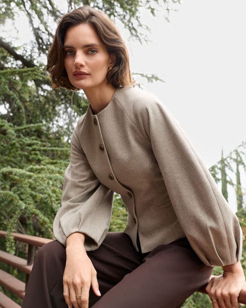 A woman in a brown collarless balloon-sleeve jacket. 