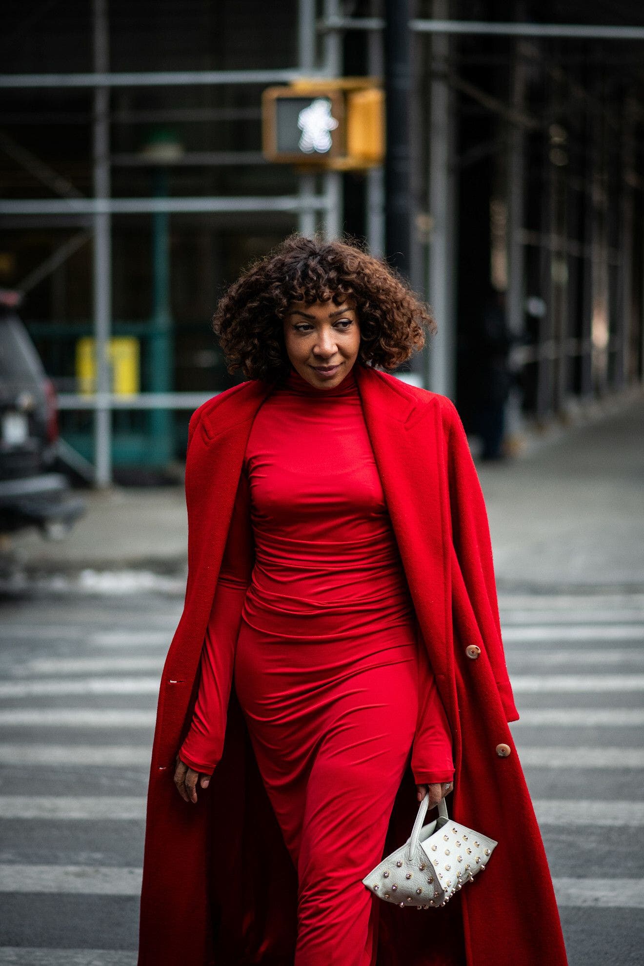 Woman in a red dress and coat at New York Fashion Week.