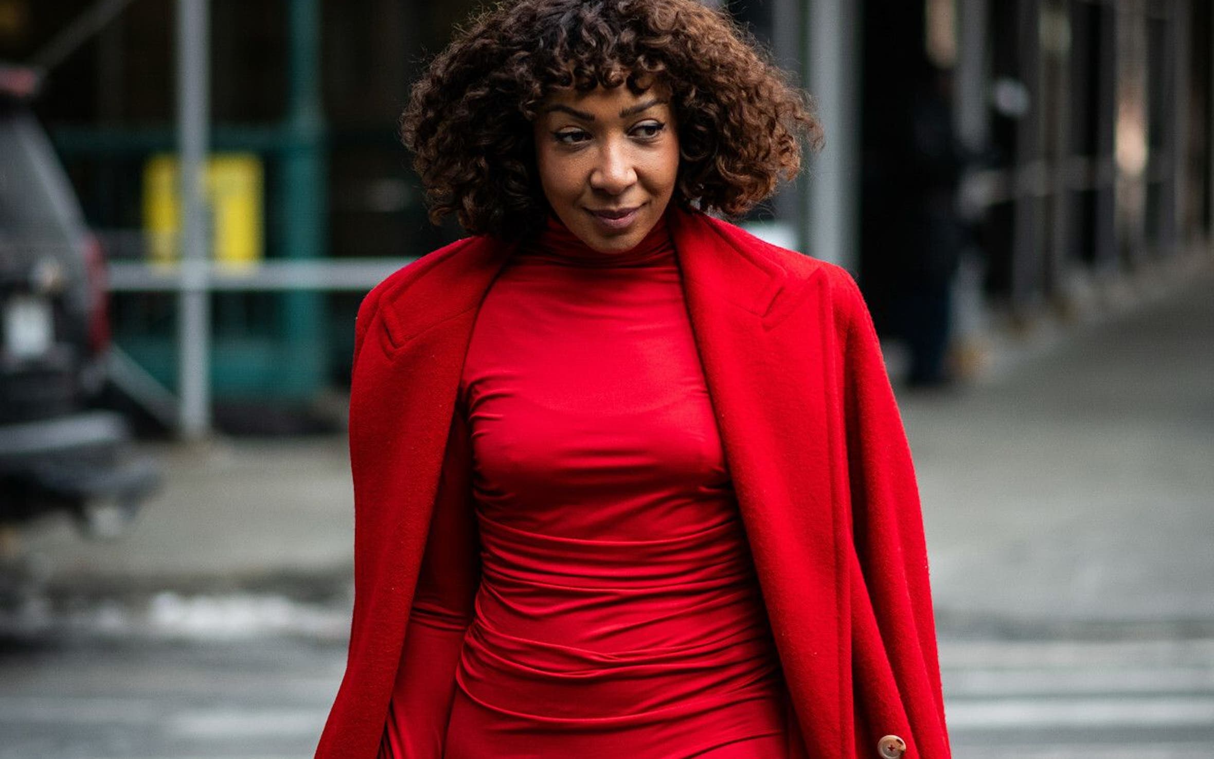 Woman in a red dress and coat at New York Fashion Week.