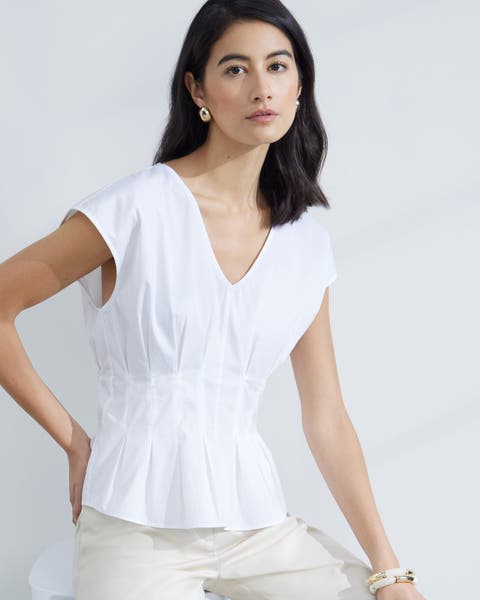 Woman wearing a white top and cream pants.