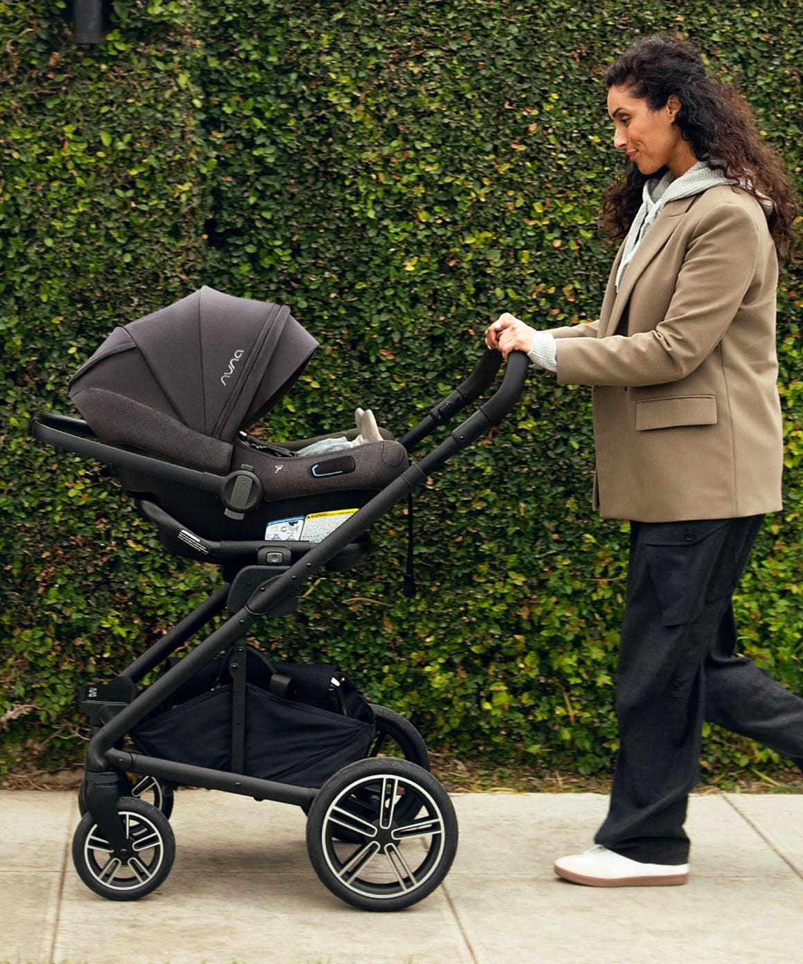 A woman pushing a Nuna stroller.