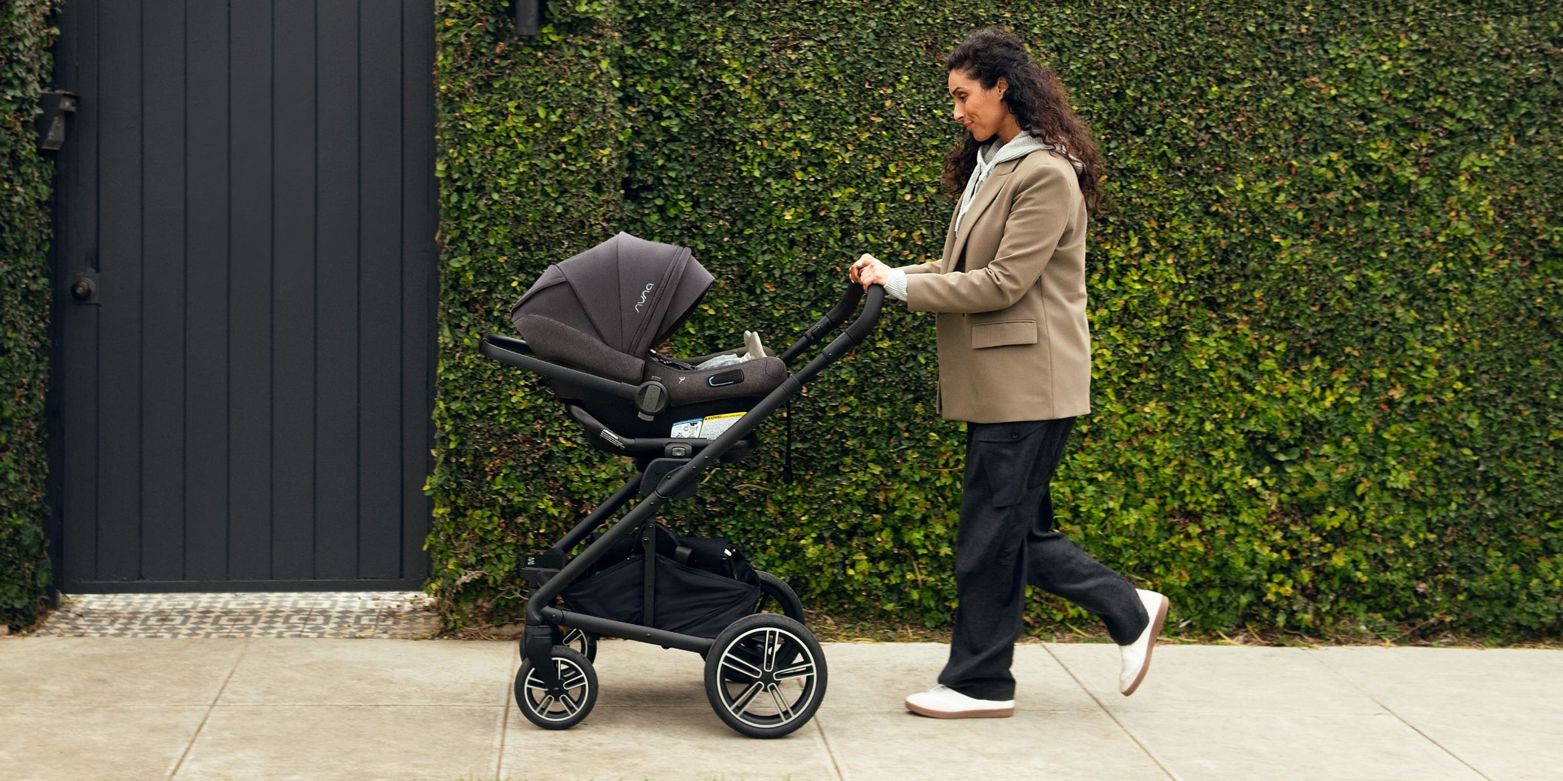 A woman pushing a Nuna stroller.