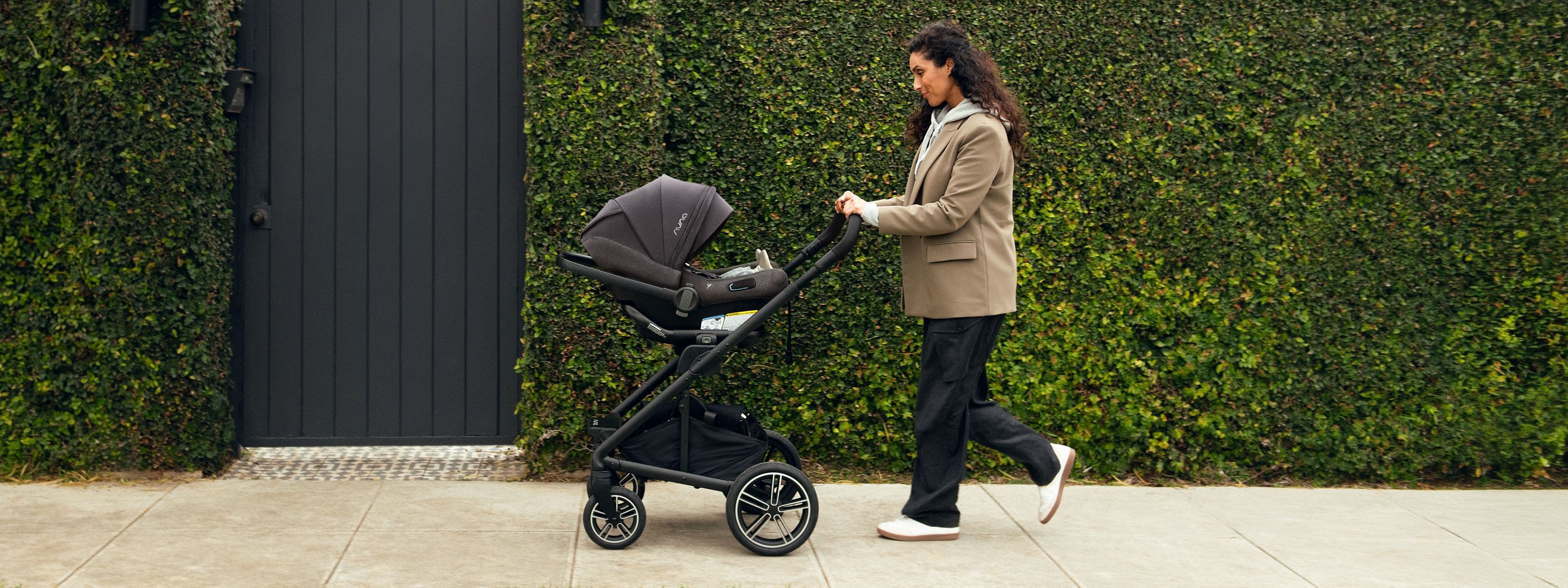 A woman pushing a Nuna stroller.