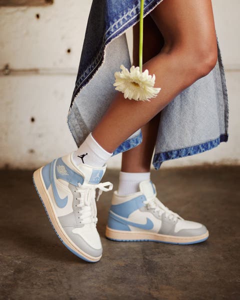 Woman wearing blue and white Nike high-top sneakers with white Jordan socks.