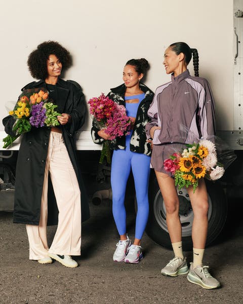 Three women wearing Nike sets holding flower bouquets.