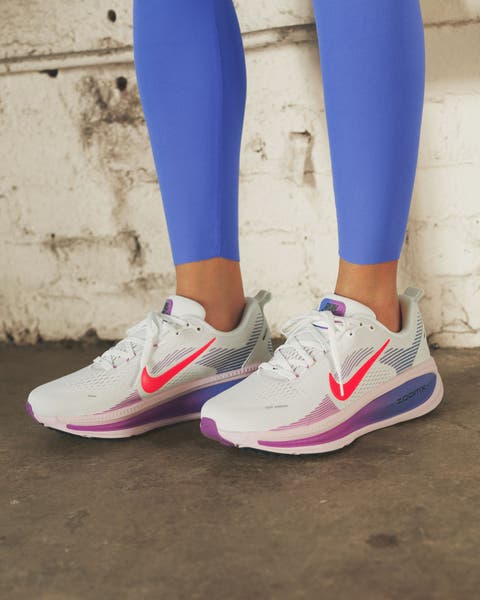 Woman wearing white and pink Nike running shoes with bright blue leggings.