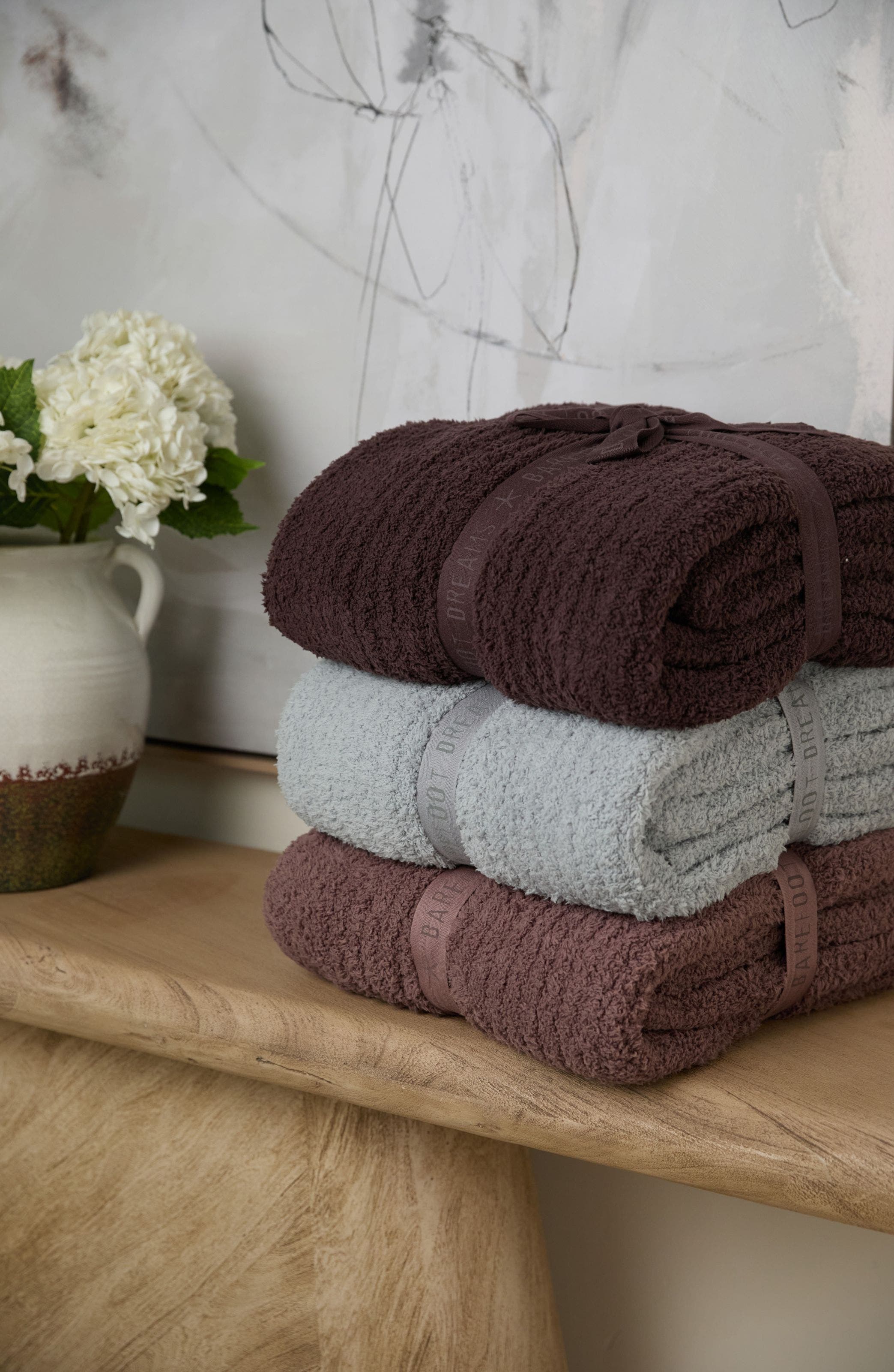 A stack of three Barefoot Dreams blankets.