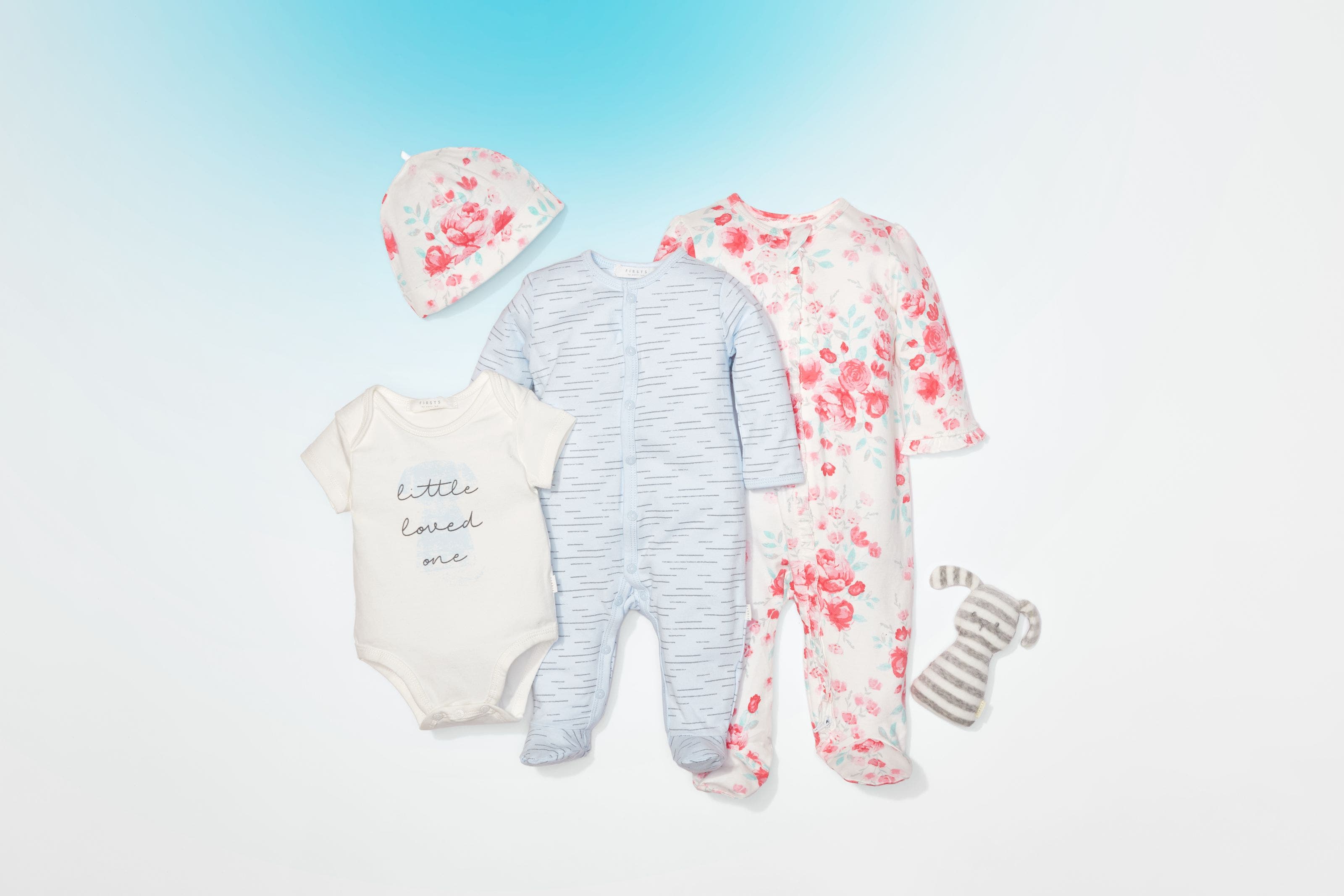An array of baby clothing and a stuffed toy.