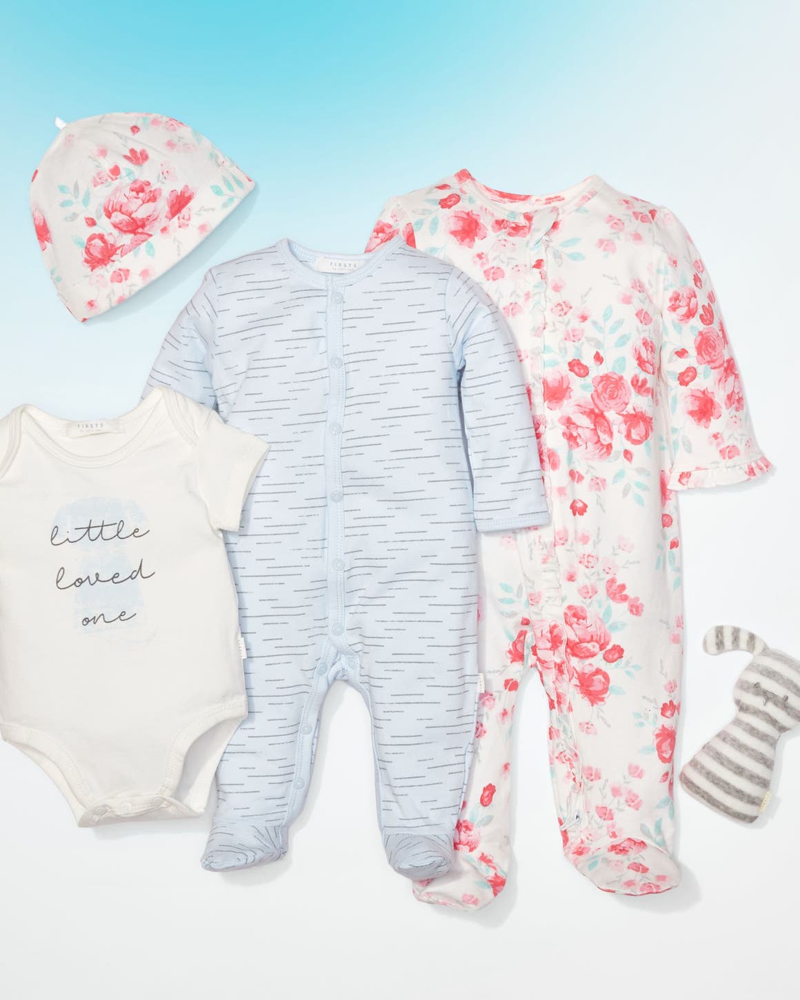 An array of baby clothing and a stuffed toy.