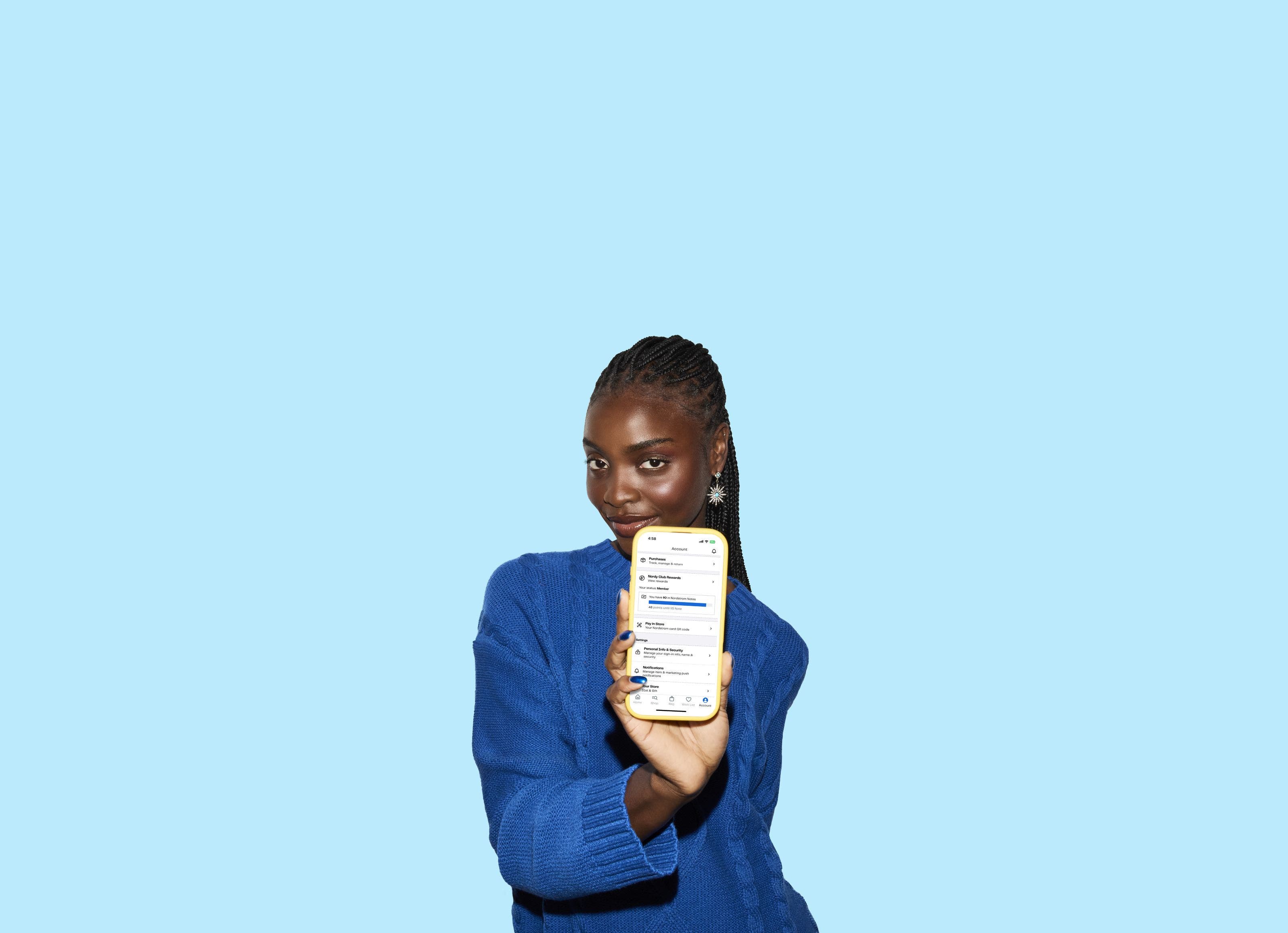 A woman holding up a cell phone showing the Nordstrom Rack app.