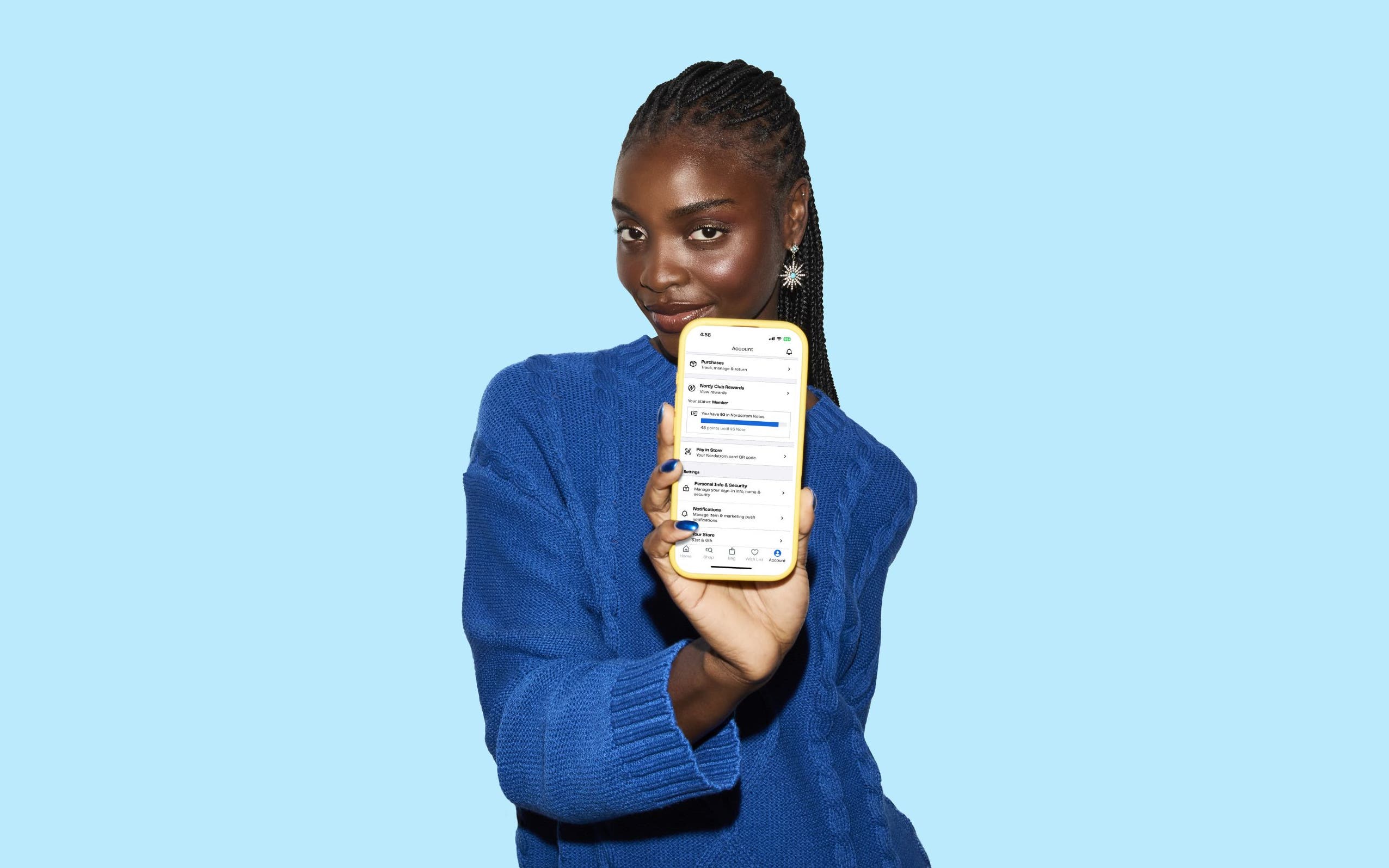 A woman holding up a cell phone showing the Nordstrom Rack app.