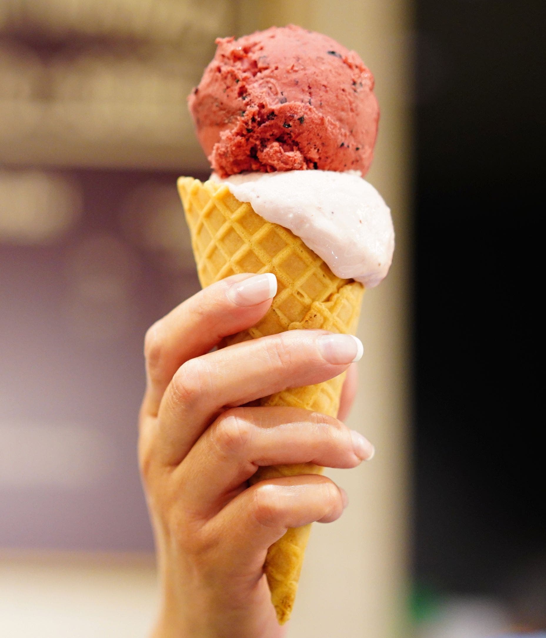 Hand holding a waffle cone filled with gelato.