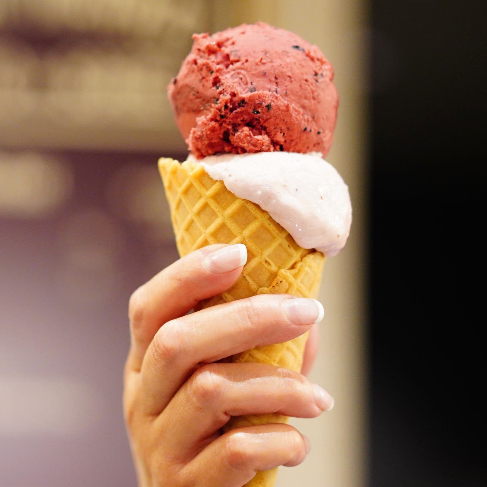 Hand holding a waffle cone filled with gelato.