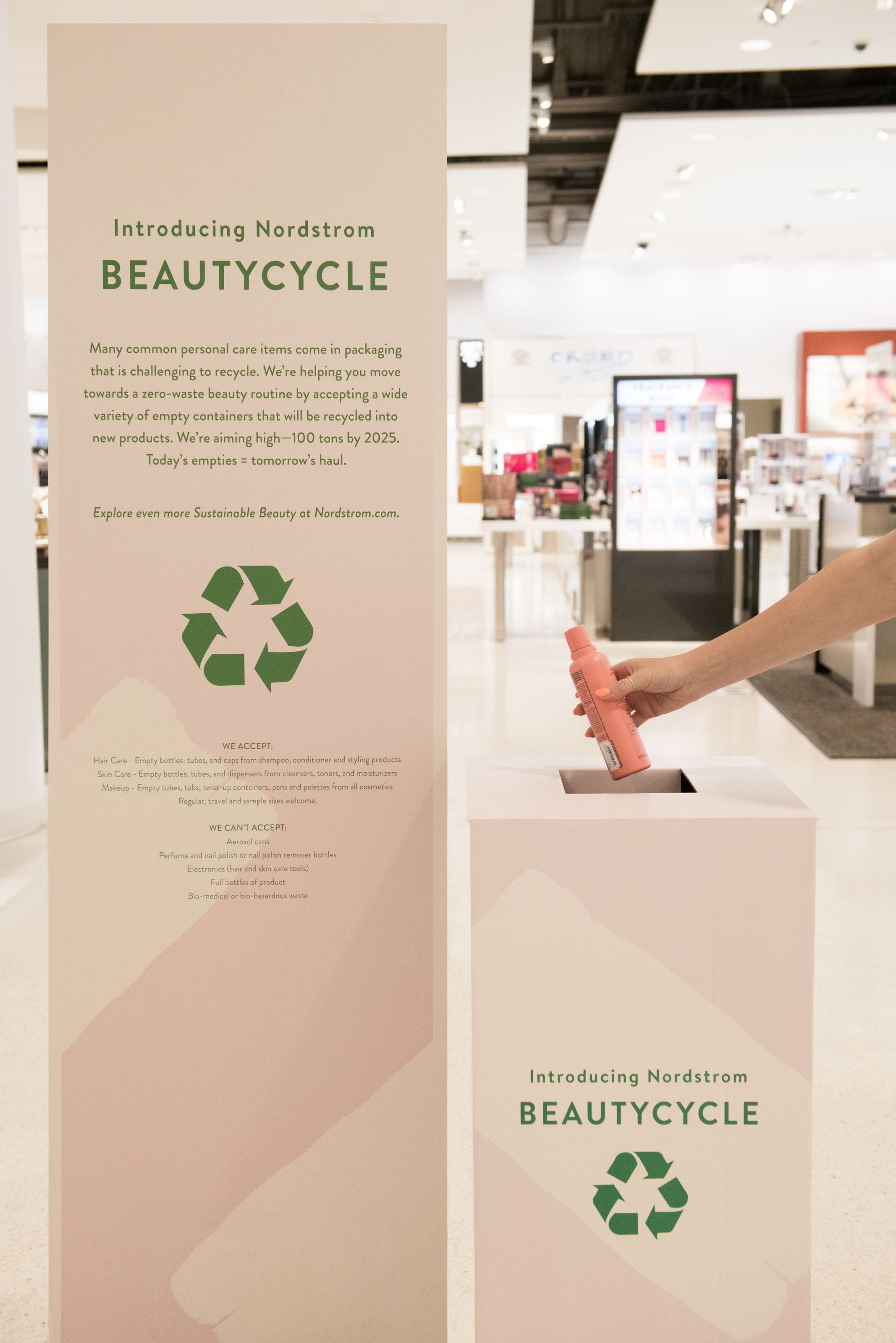 An empty shampoo bottle being placed in a BeautyCycle bin.