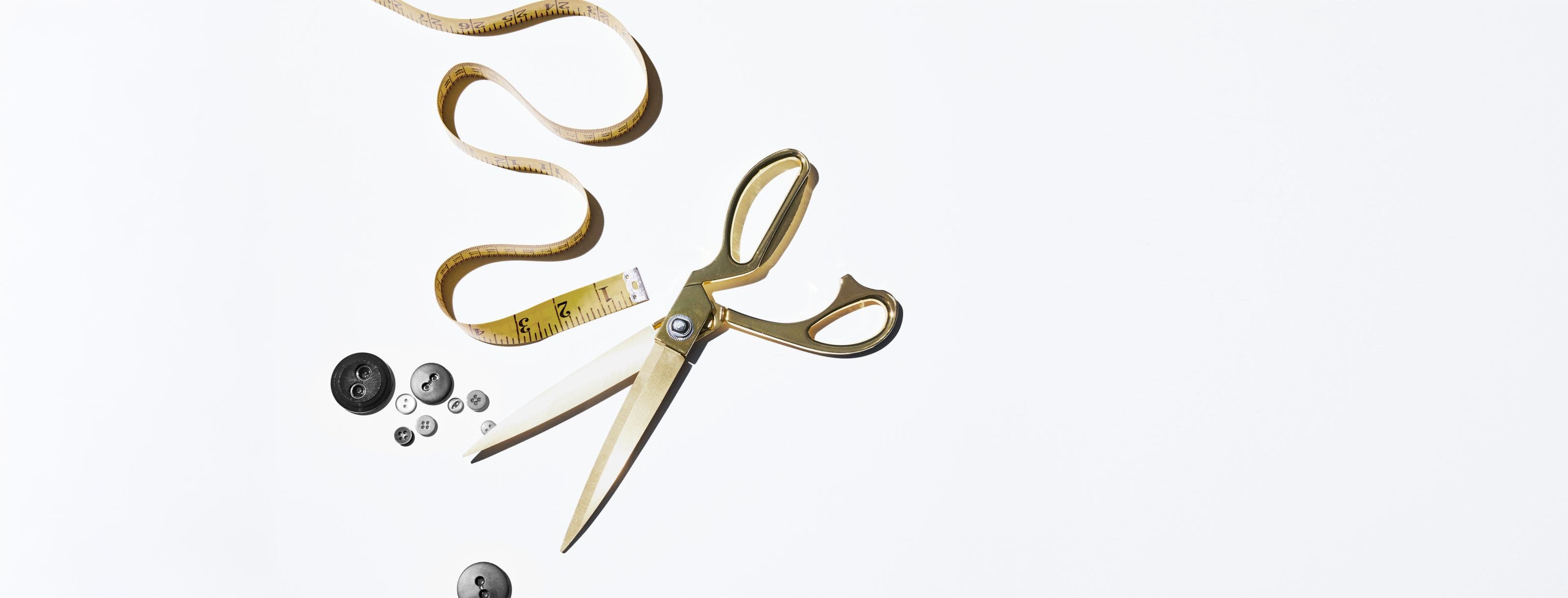 Tailor's scissors, measuring tape and buttons.