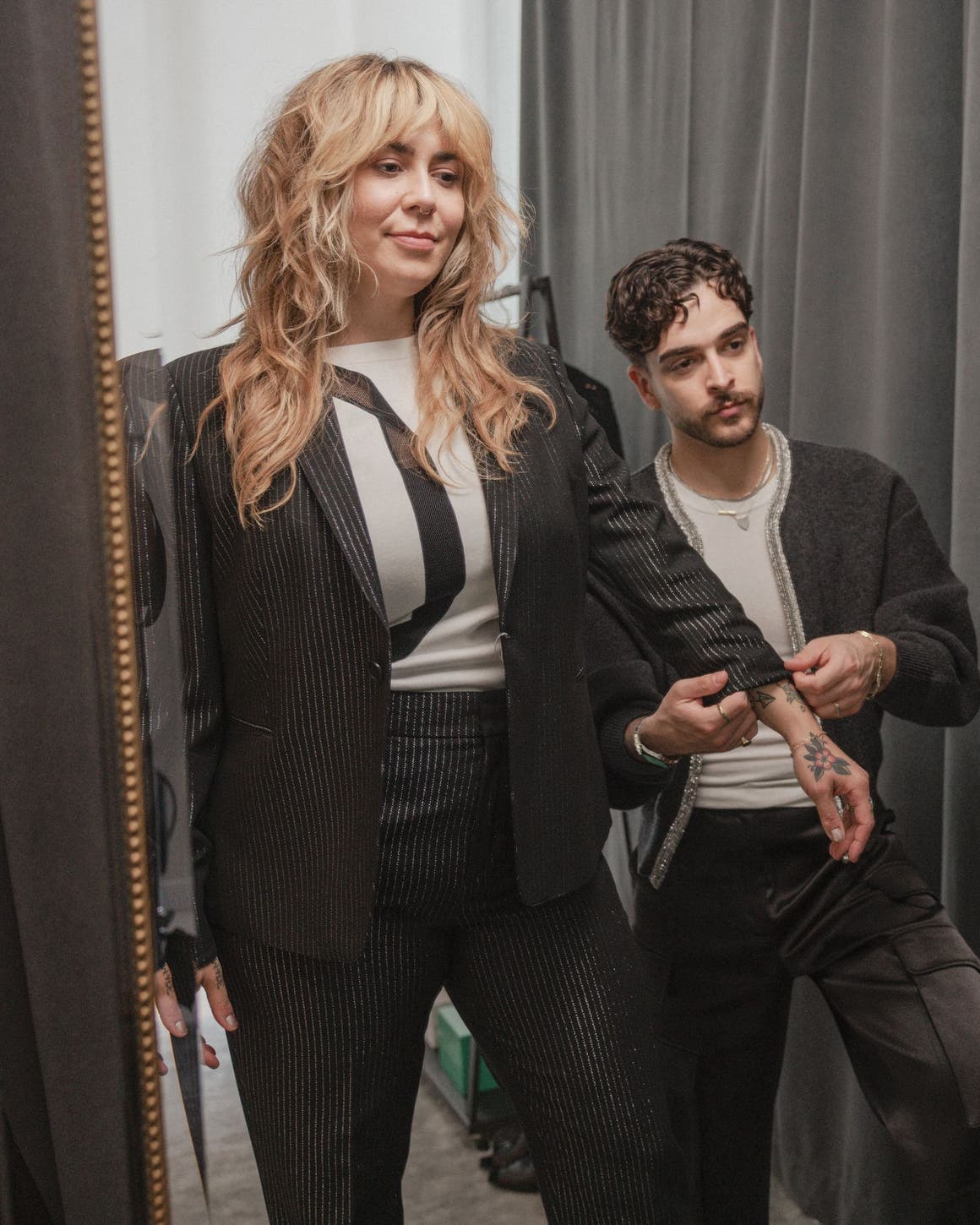 A stylist adjusting a woman's sleeve.