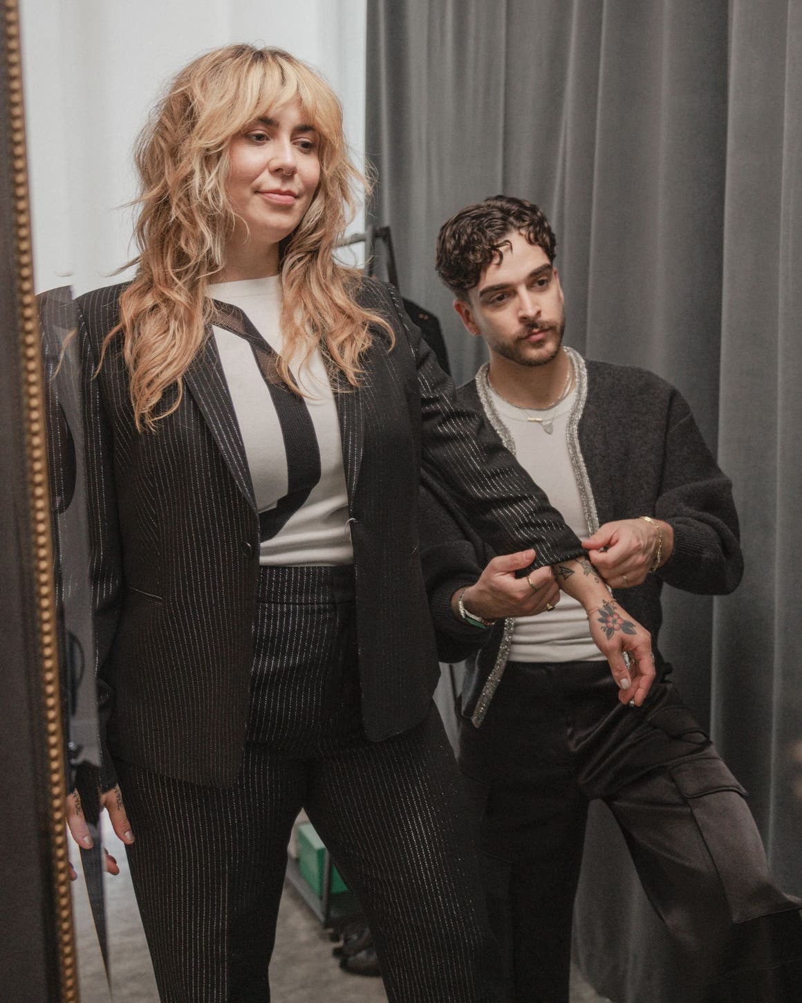 A stylist adjusting a woman's sleeve.