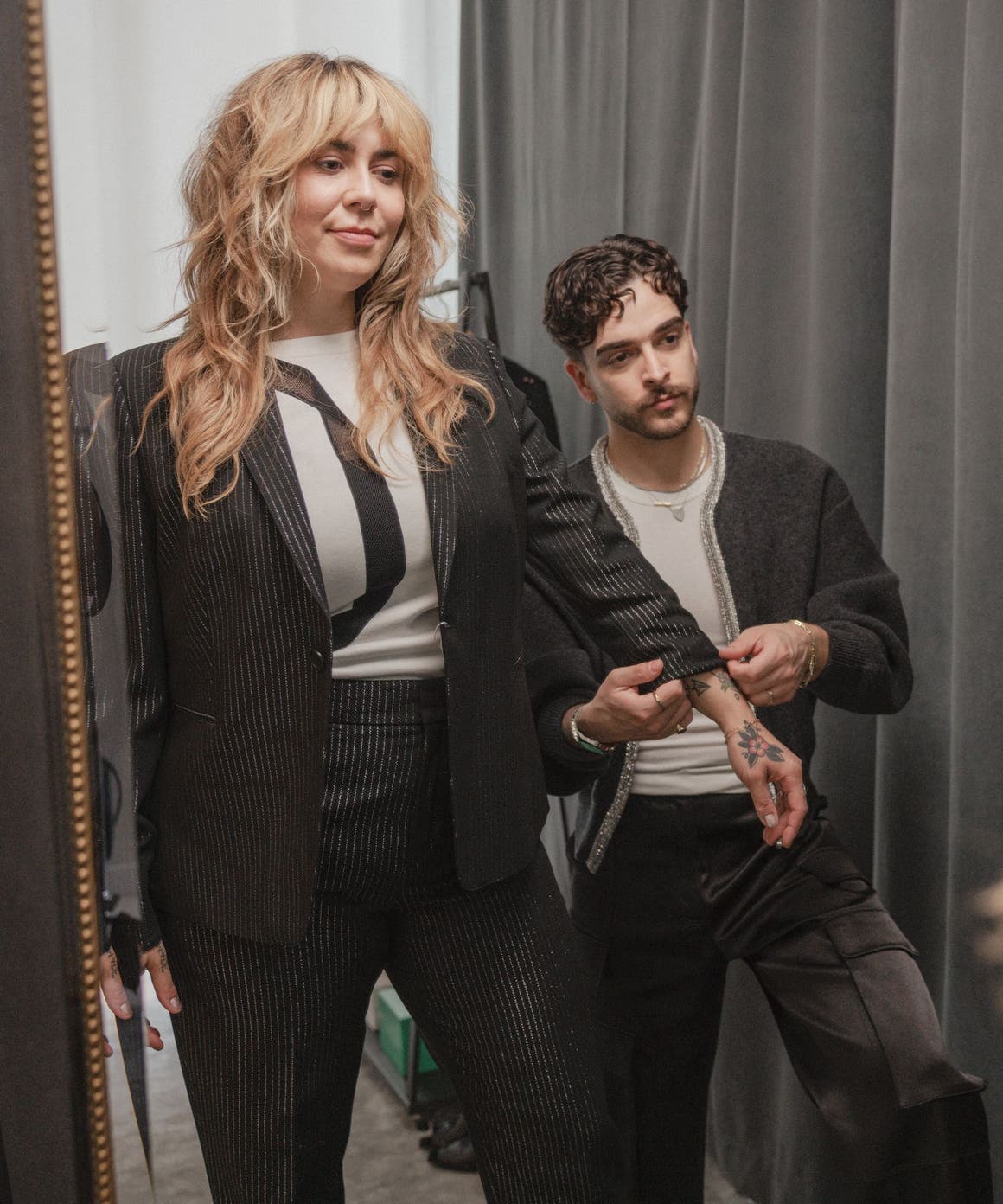 A stylist adjusting a woman's sleeve.