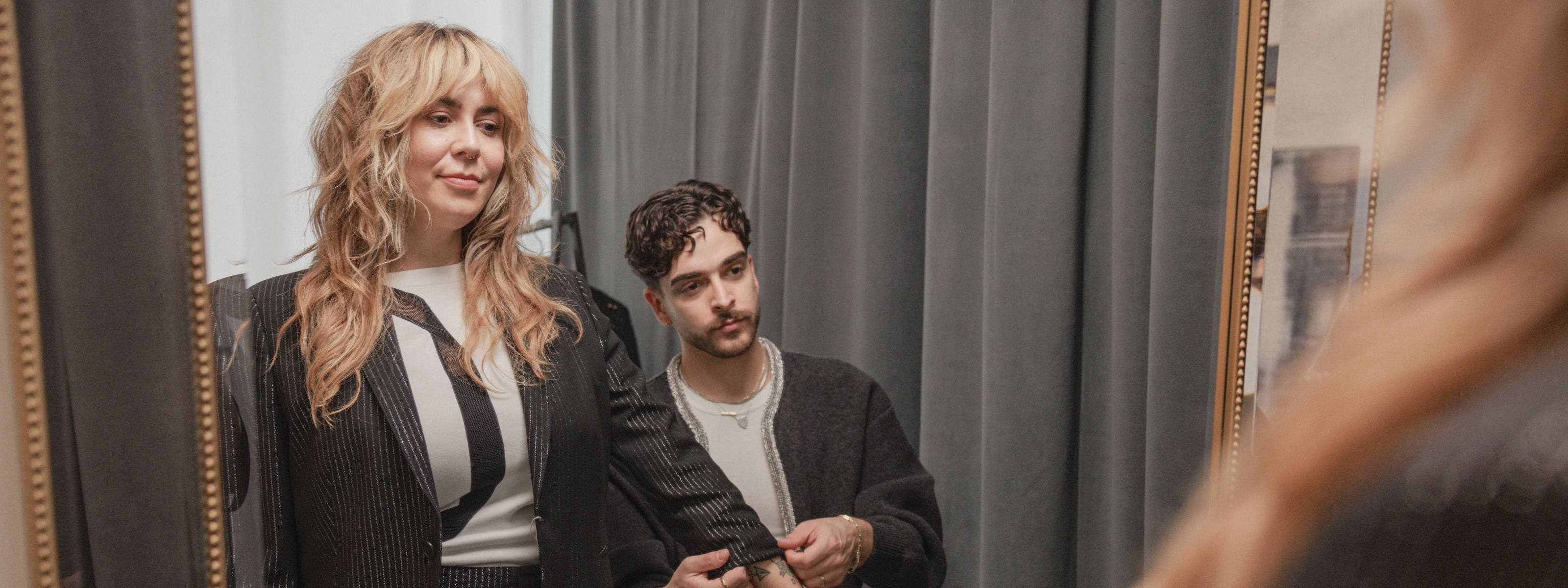 A stylist adjusting a woman's sleeve.