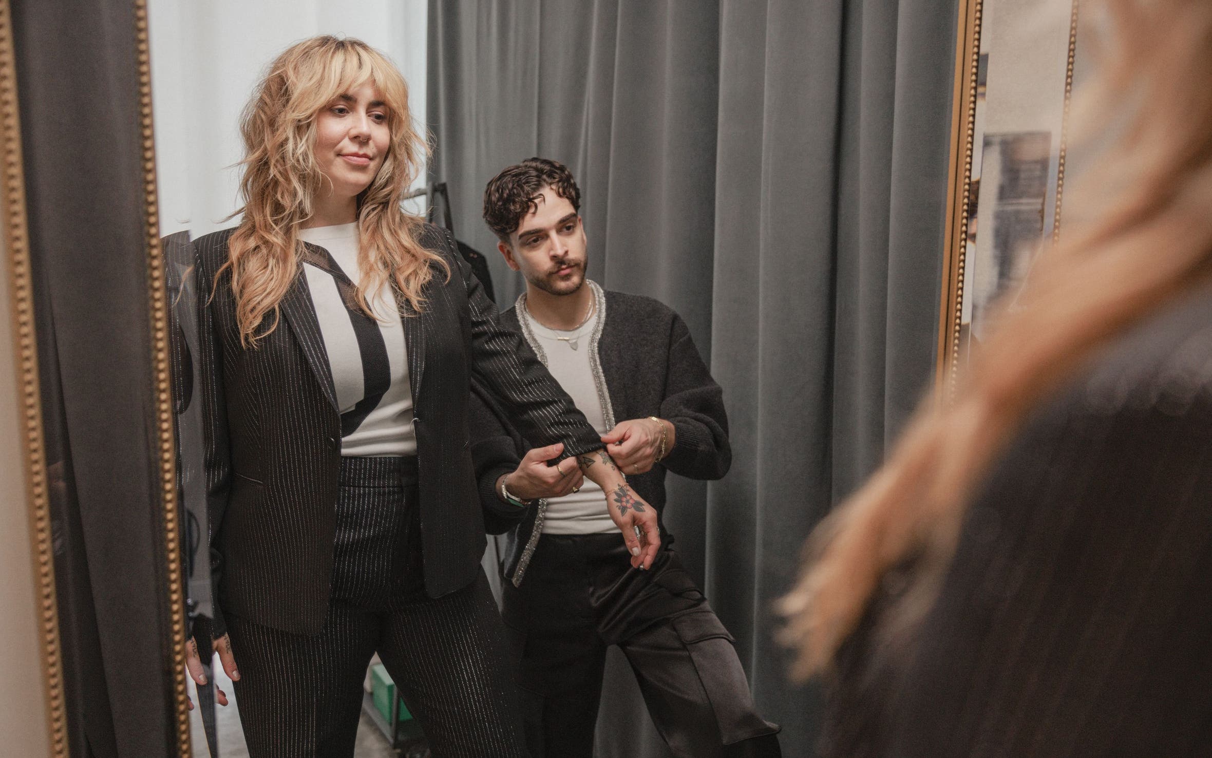 A stylist adjusting a woman's sleeve.