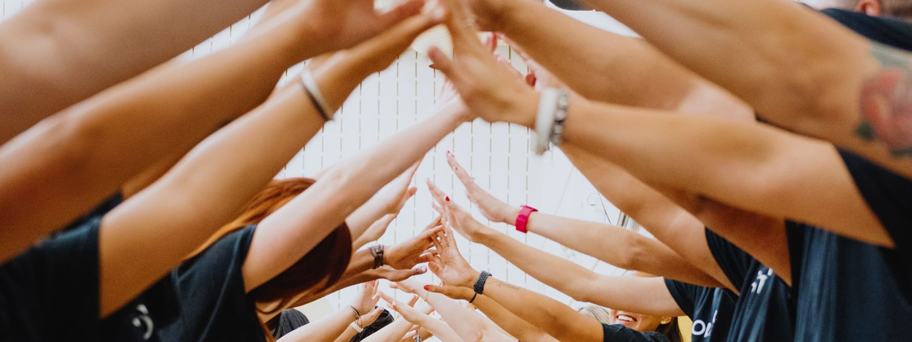 A line of Nordstrom volunteers facing each other and touching fingers.