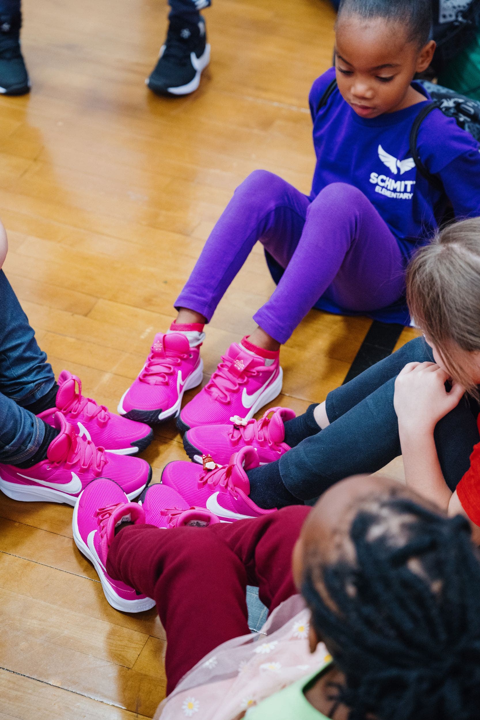 A group of kids check out their feet in new hot-pink sneakers.  