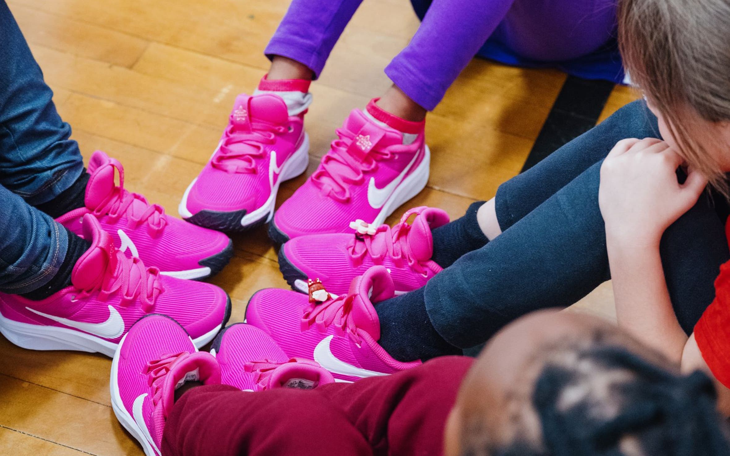 A group of kids check out their feet in new hot-pink sneakers.