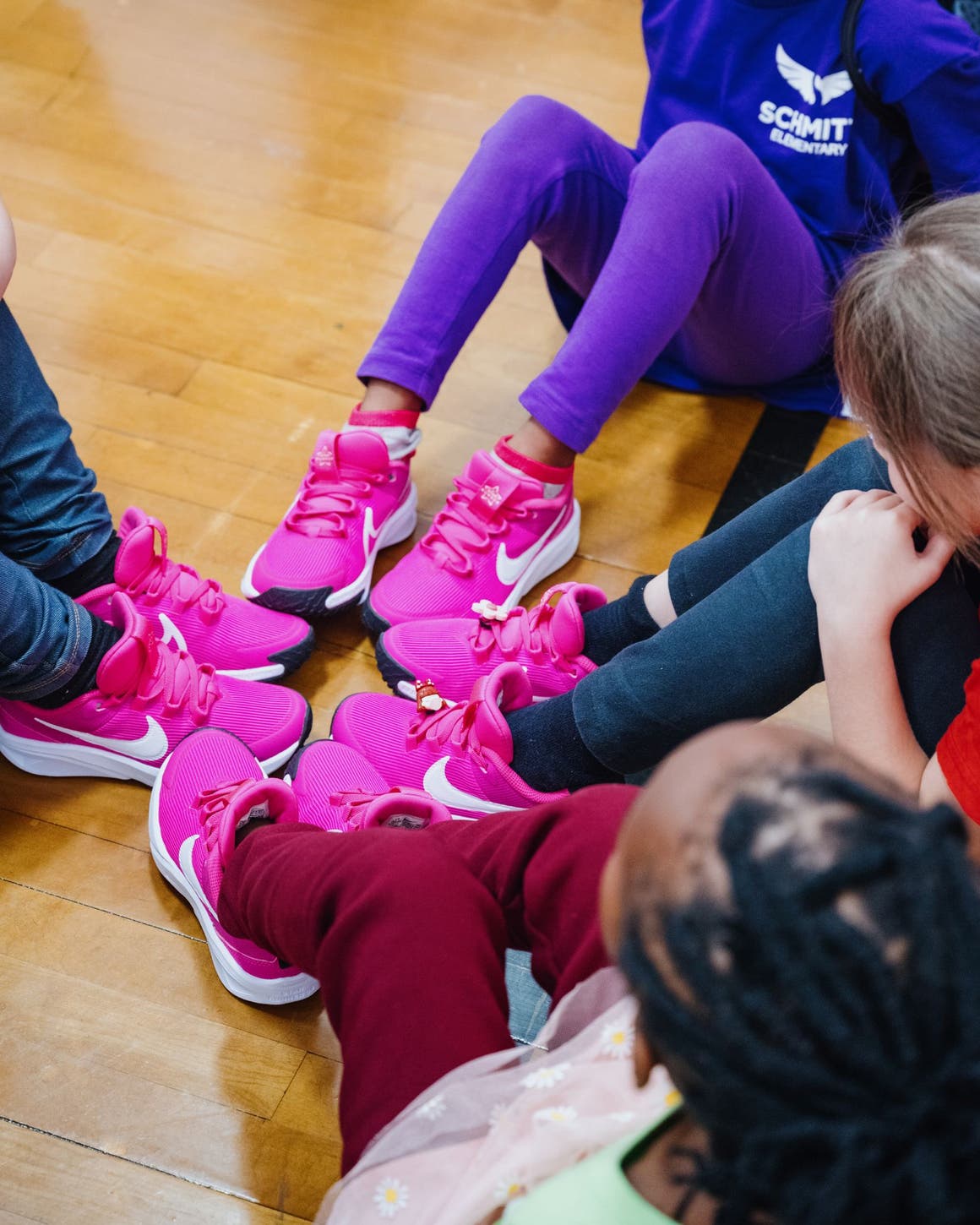 A group of kids check out their feet in new hot-pink sneakers.