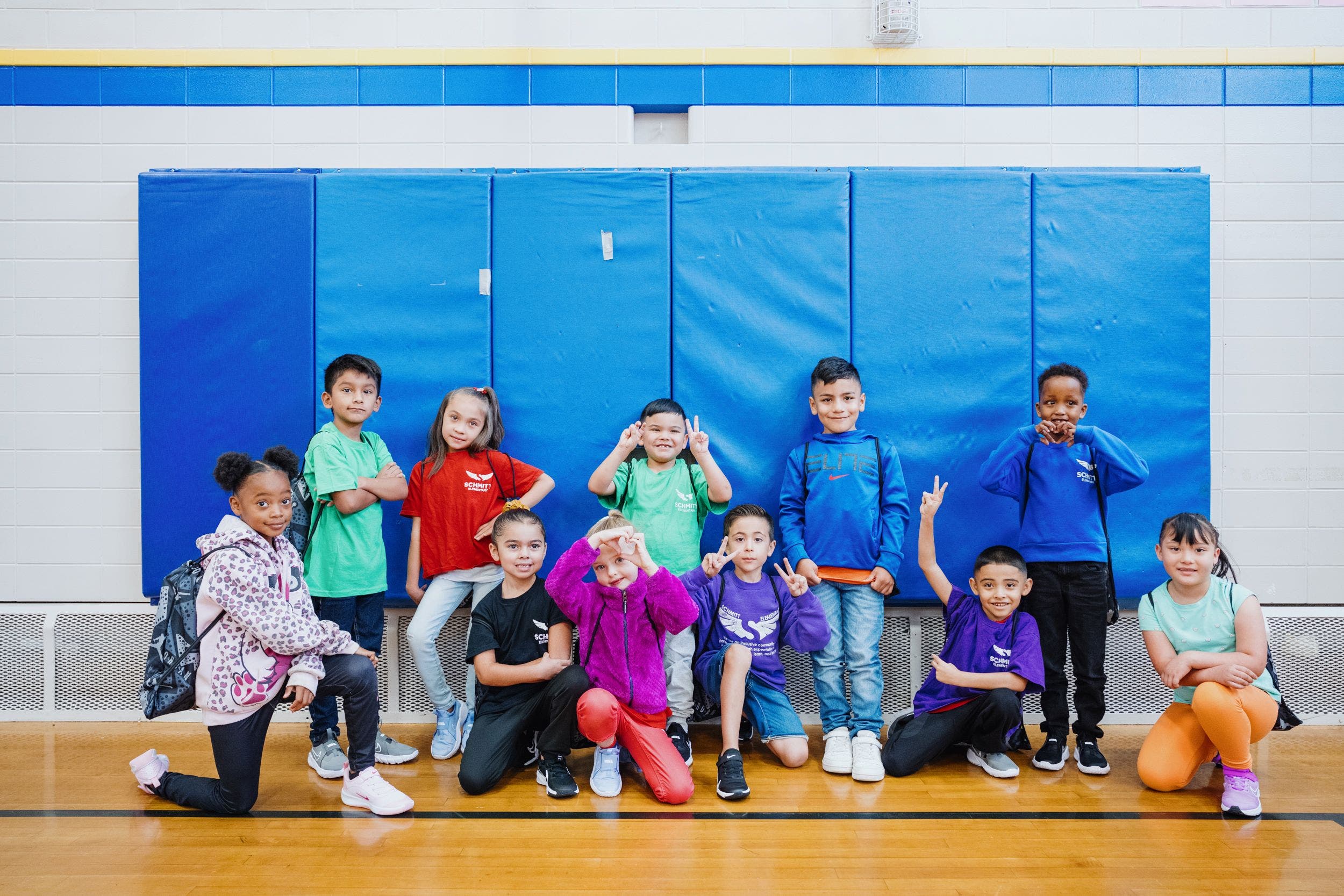 Kids pose in a school gym with their new shoes. 