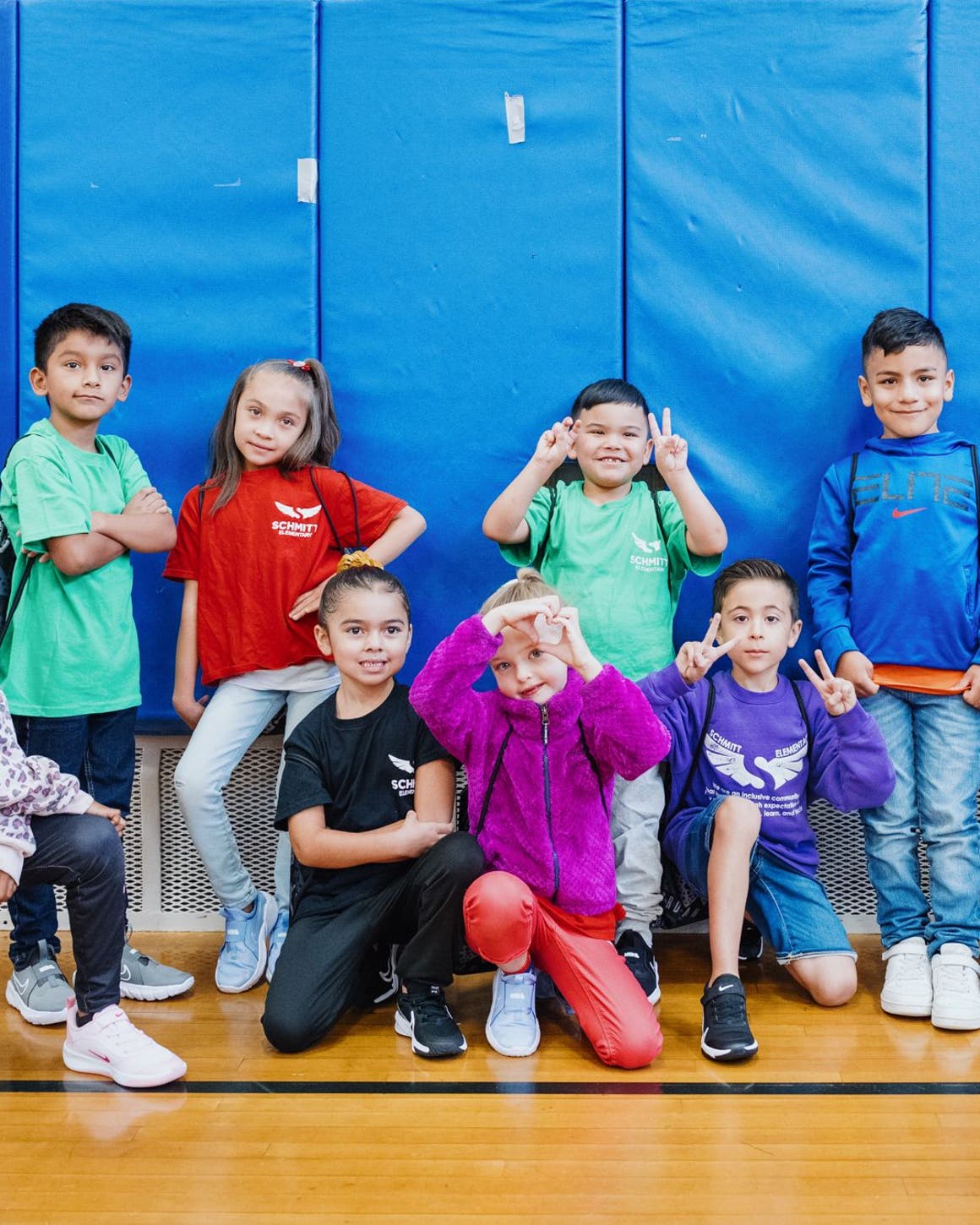Kids pose in a school gym with their new shoes.