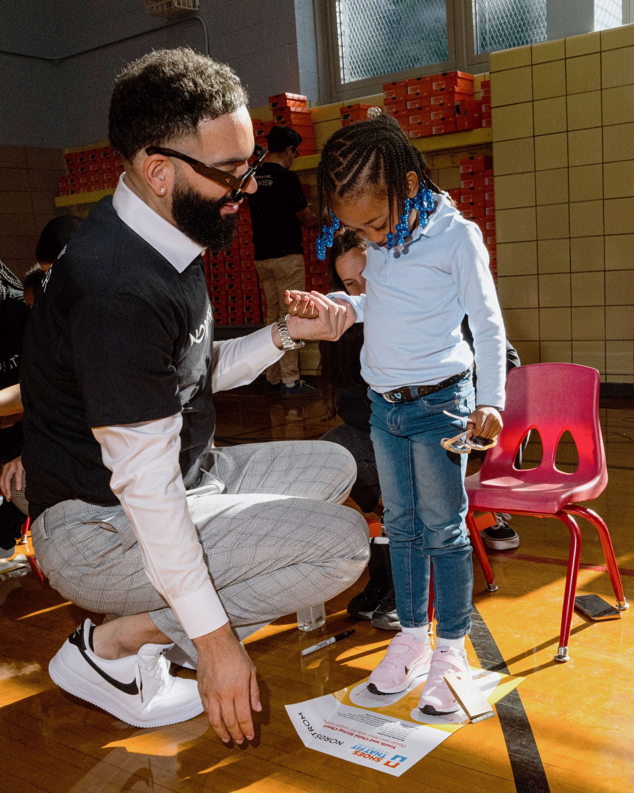 A man helping a little girl try on new Nike sneakers. 