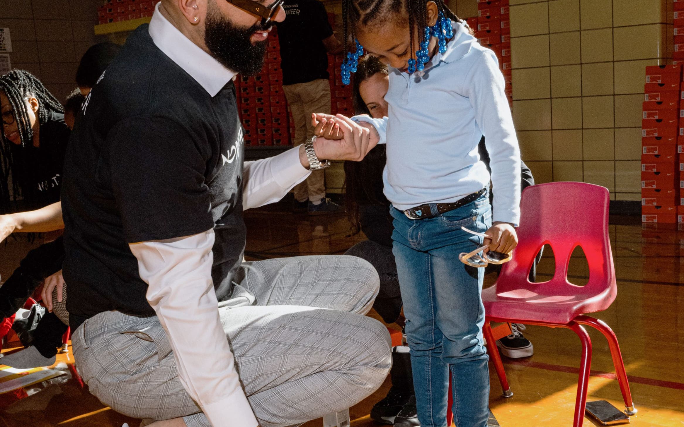 A man helping a little girl try on new Nike sneakers. 