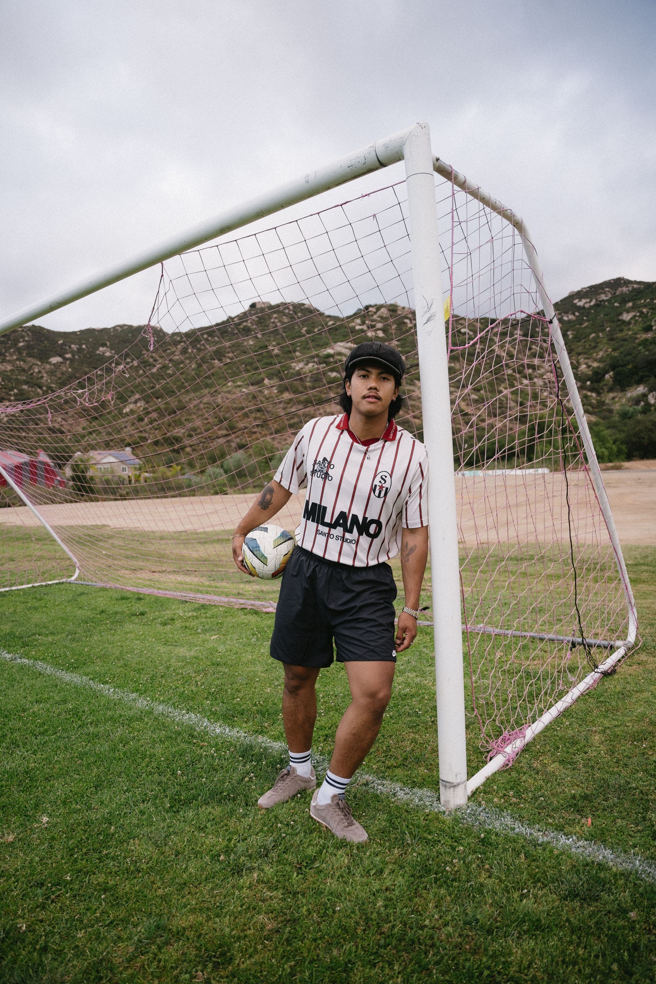 Man wearing soccer jersey and black shorts, holding a soccer ball.