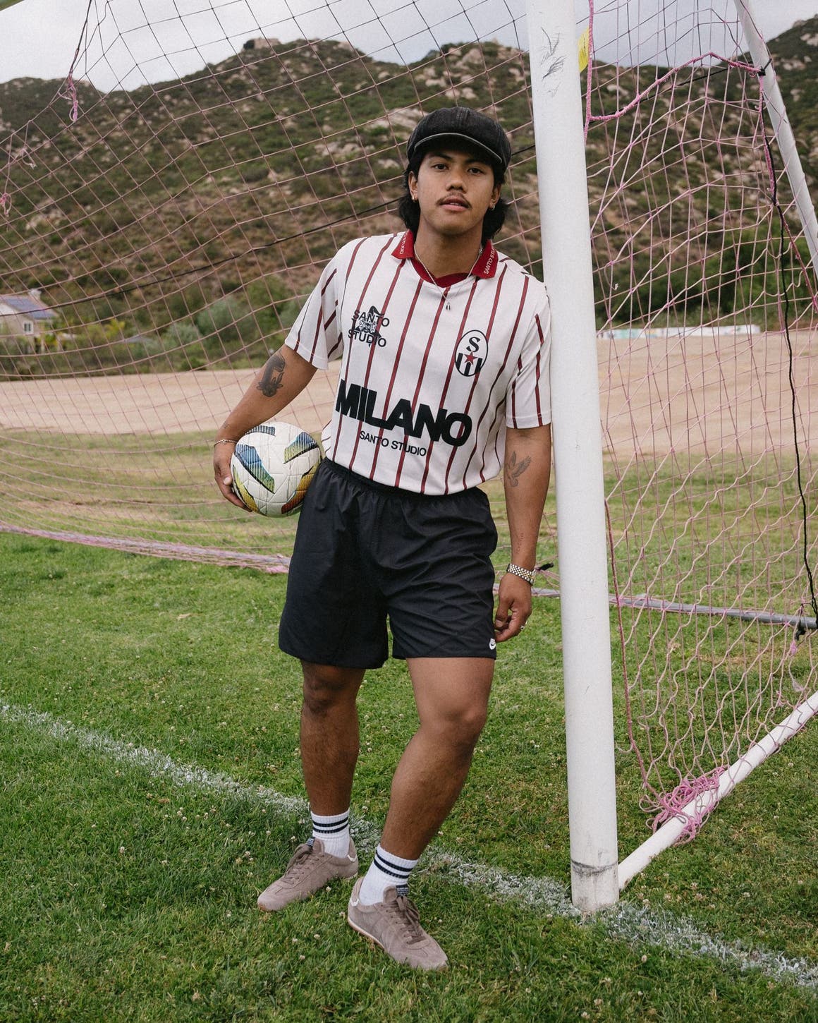 Man wearing soccer jersey and black shorts, holding a soccer ball.