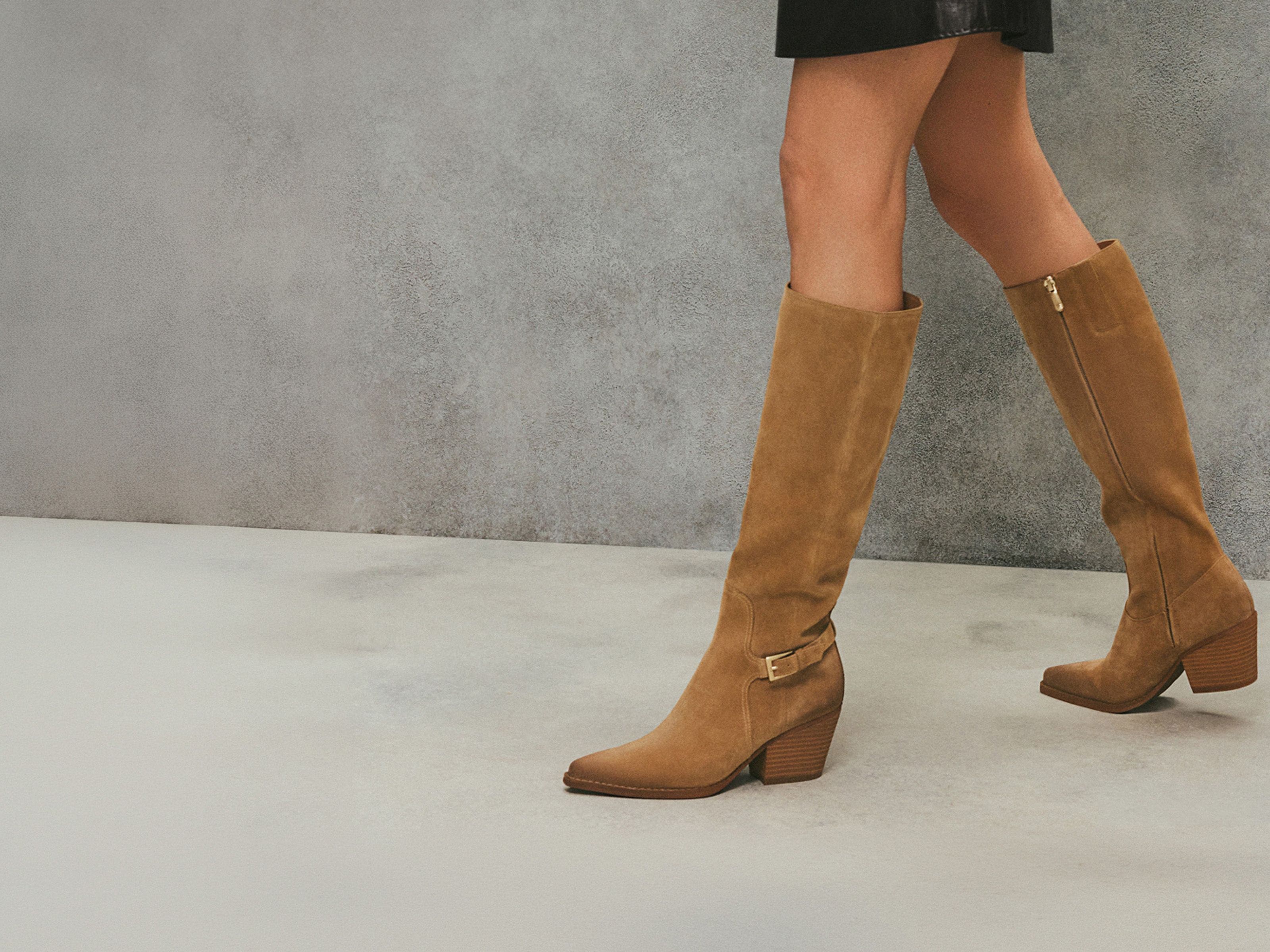 Woman wearing tan knee-high Sam Edelman boots.