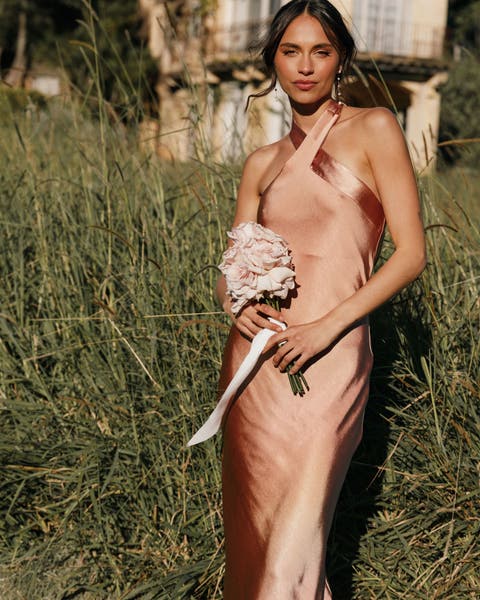 A woman in a champagne bridesmaid dress holding a bouquet. 