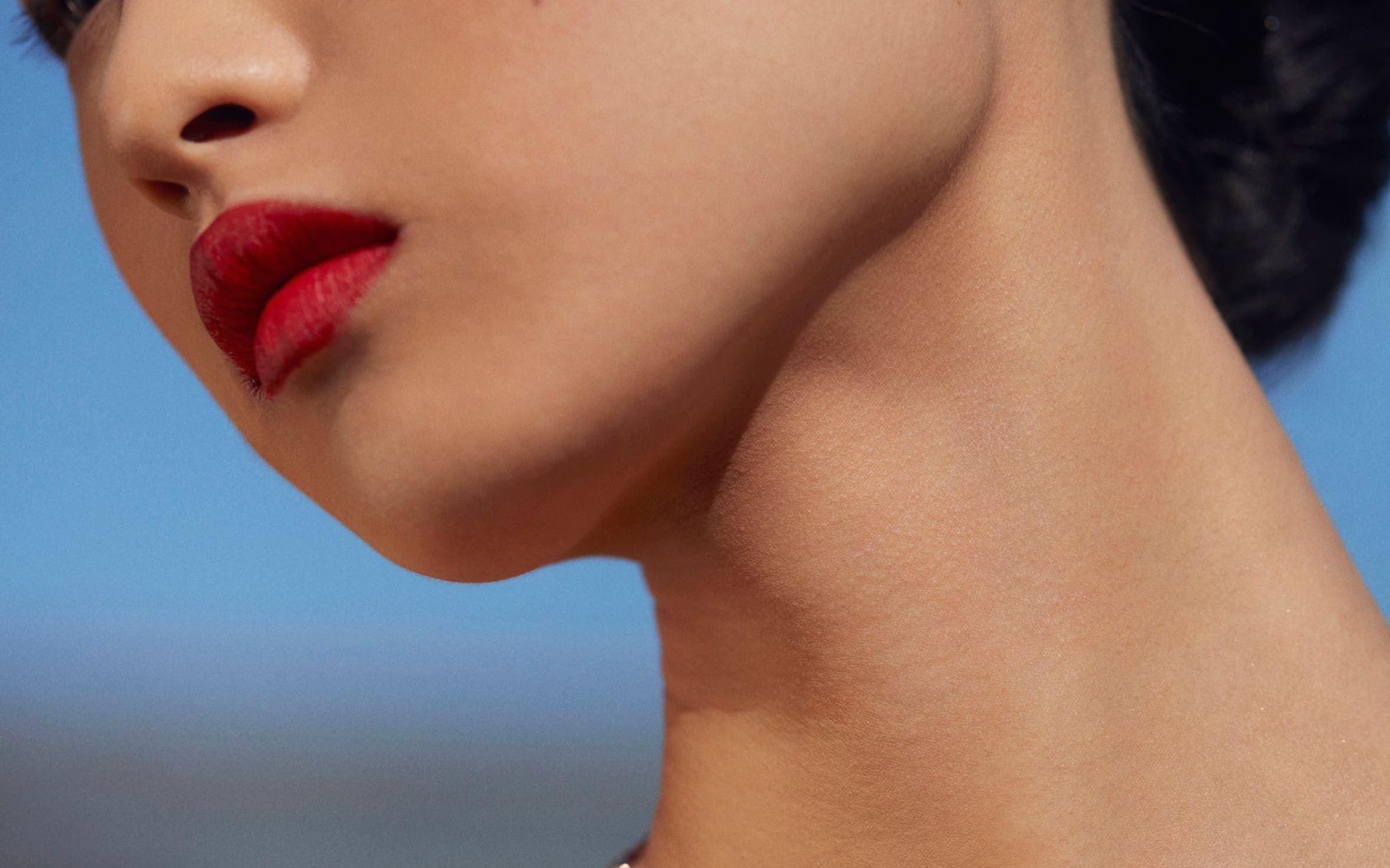 Woman wearing earrings and three necklaces in different colors from Monica Vinader.