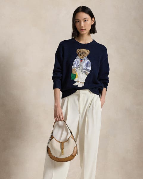 A woman wearing a sweater with an embellished bear. 