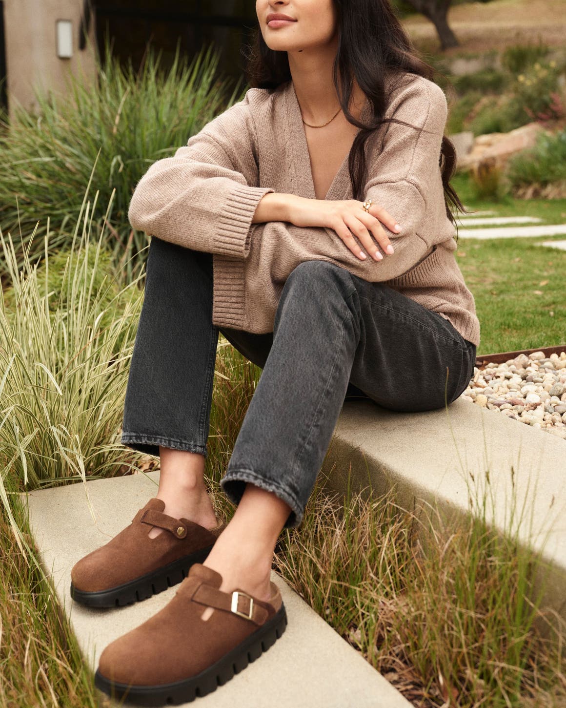 A woman wearing brown suede clogs with chunky platform soles.