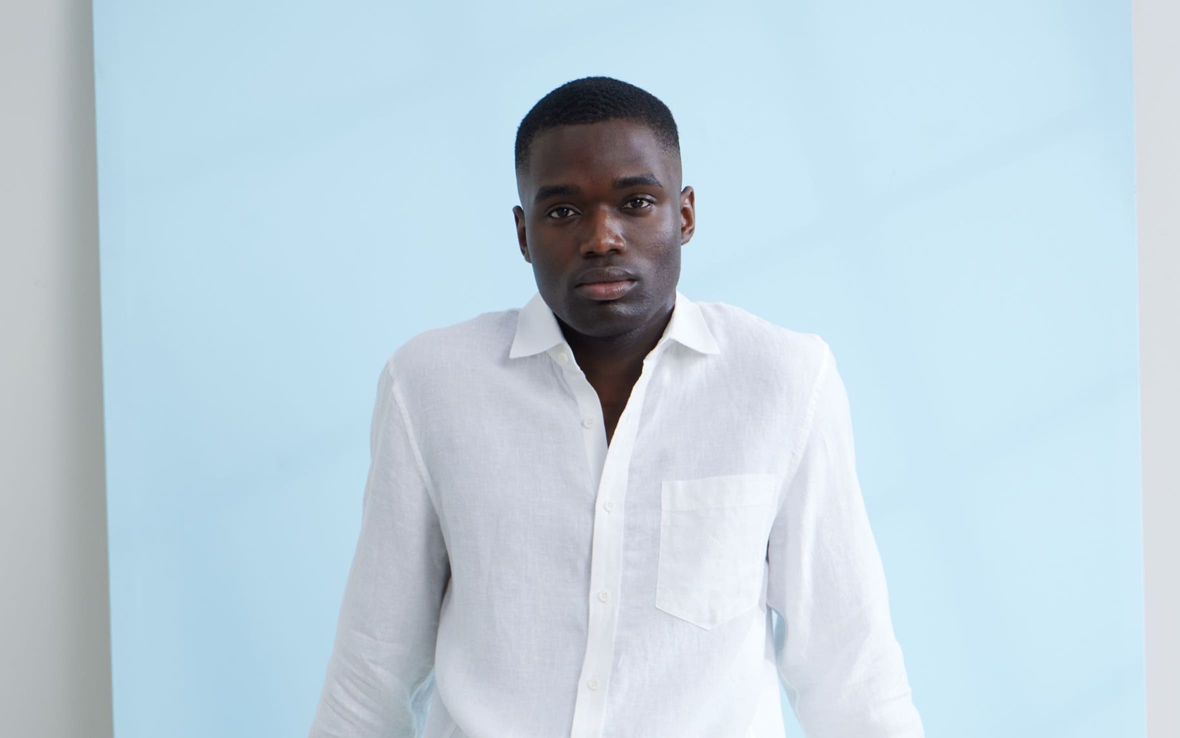 A man wearing a white button-up shirt and brown shorts.