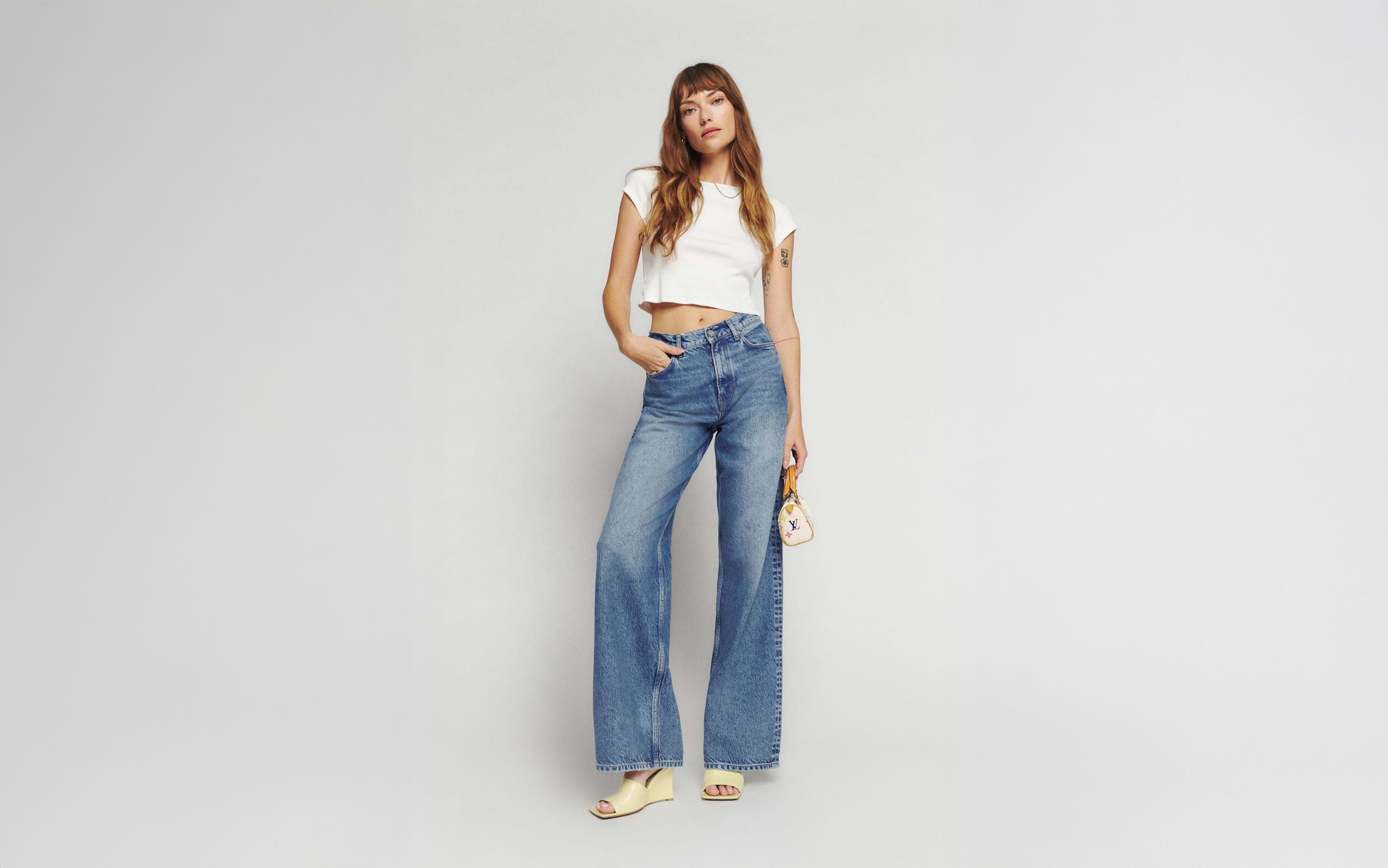 A woman wearing a white tee and jeans.