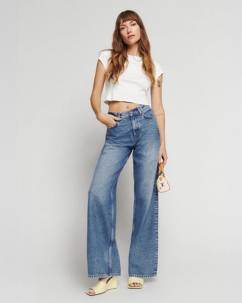 A woman wearing a white tee and jeans.