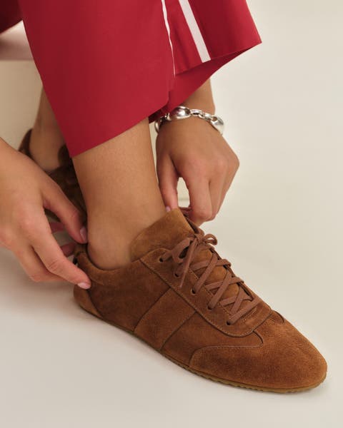 A woman wearing a brown suede sneaker.